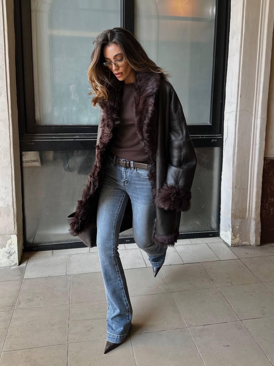 Идея осеннего образа от Марии Кузьминой. Сочетаем расклешенные джинсы и шерстяную футболку с туфлями на высоком каблуке, а в качестве верхнего слоя выбираем двустороннюю дубленку из натуральной кожи с объемным кудрявым мехом.